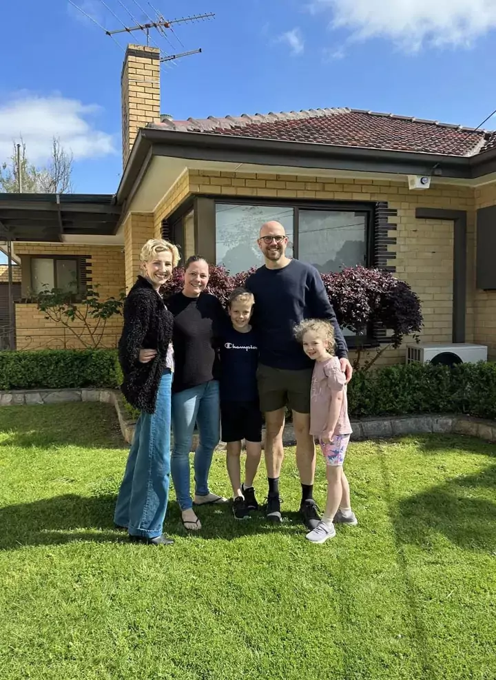 happy-clients-with-their-new-home Smiling clients standing in front of their new home with their buyers agent for investment property